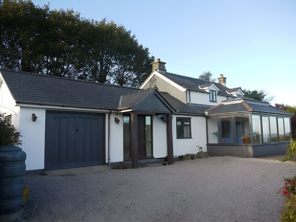 A house with a garage and conservatory at Tranquil Cottage in 