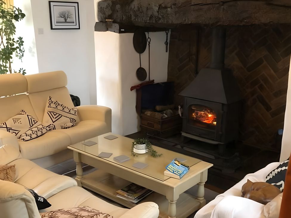 A living room with a fireplace and seating area at Tranquil Cottage