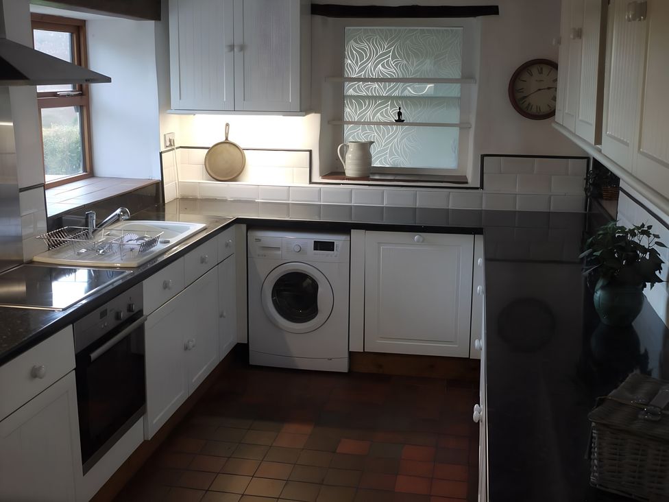 A kitchen with a sink and washing machine at Tranquil Cottage