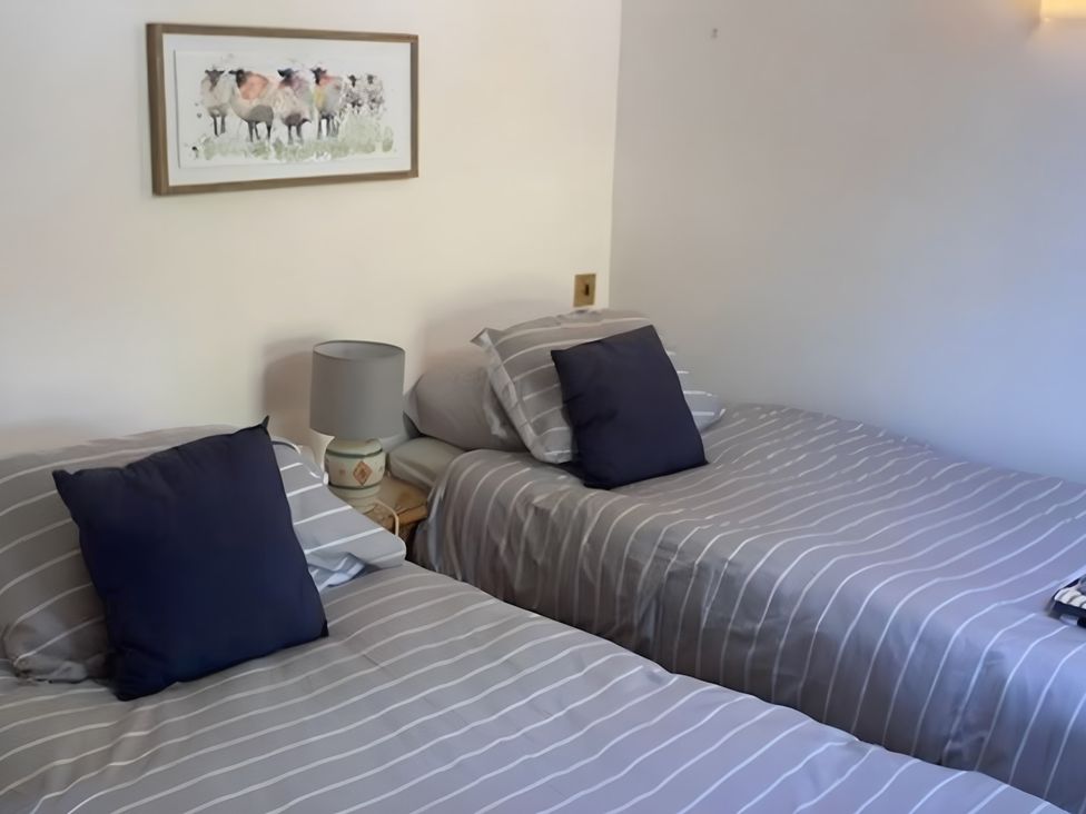 A bedroom with two single beds and a lamp at Tranquil Cottage 