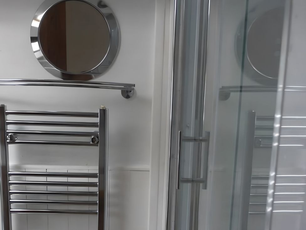 A bathroom with a mirror and towel rail at Tranquil Cottage