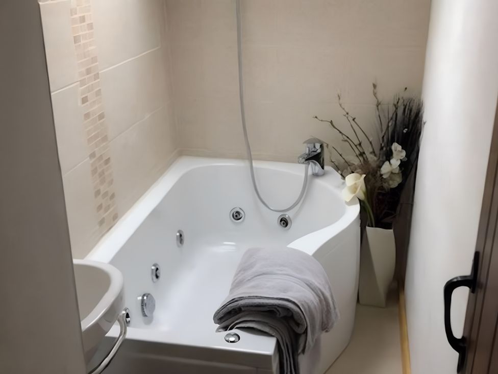 A bathroom with a bathtub and decorative plants at Tranquil Cottage