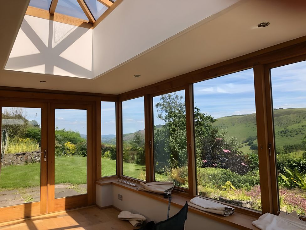 A conservatory with windows and a skylight at Tranquil Cottage