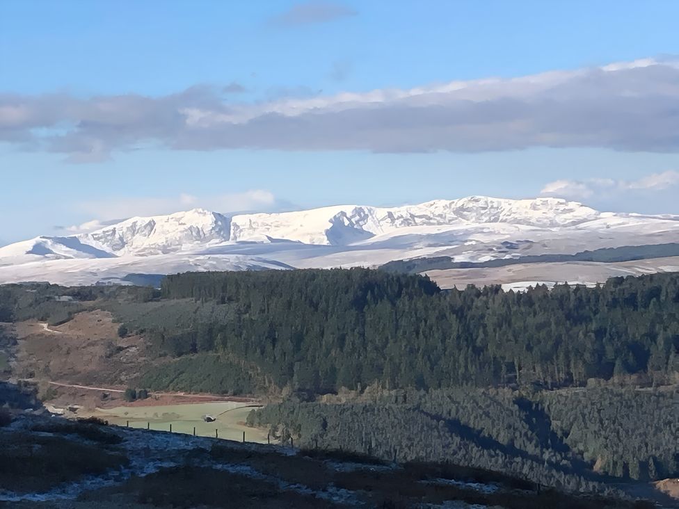A view of snow-covered mountains and forest from a distance at Tranquil Cottage