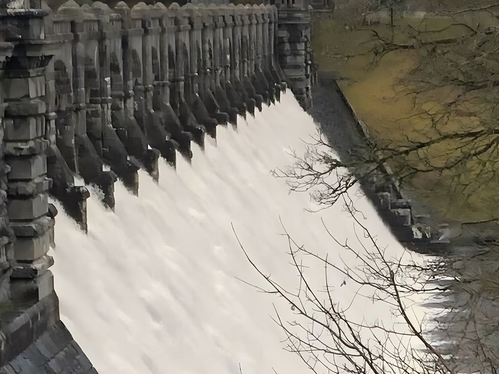 A dam releasing water with trees in the background at Tranquil Cottage 
