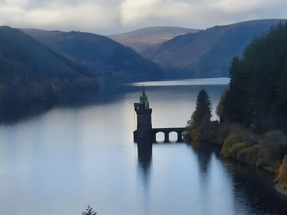 A tower on a bridge over water with mountains and trees at Tranquil Cottage in 