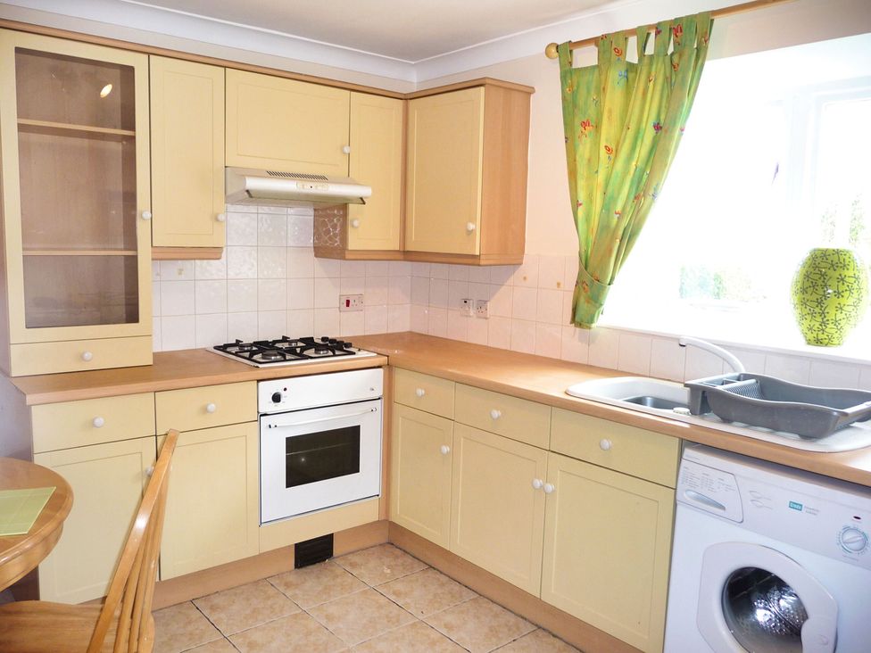 A kitchen with gas stove, oven, sink, washing machine and cabinets at 22 Homestead Garth