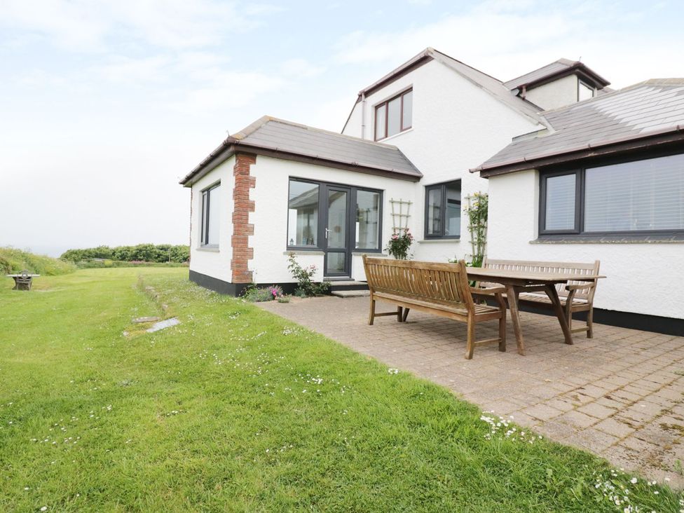 An outdoor patio with a table and bench at Chynoweth in Crantock