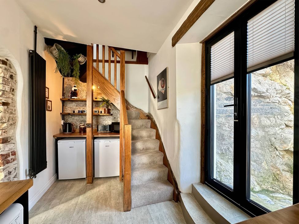 A staircase leading to a kitchen area with a refrigerator and coffee maker at 