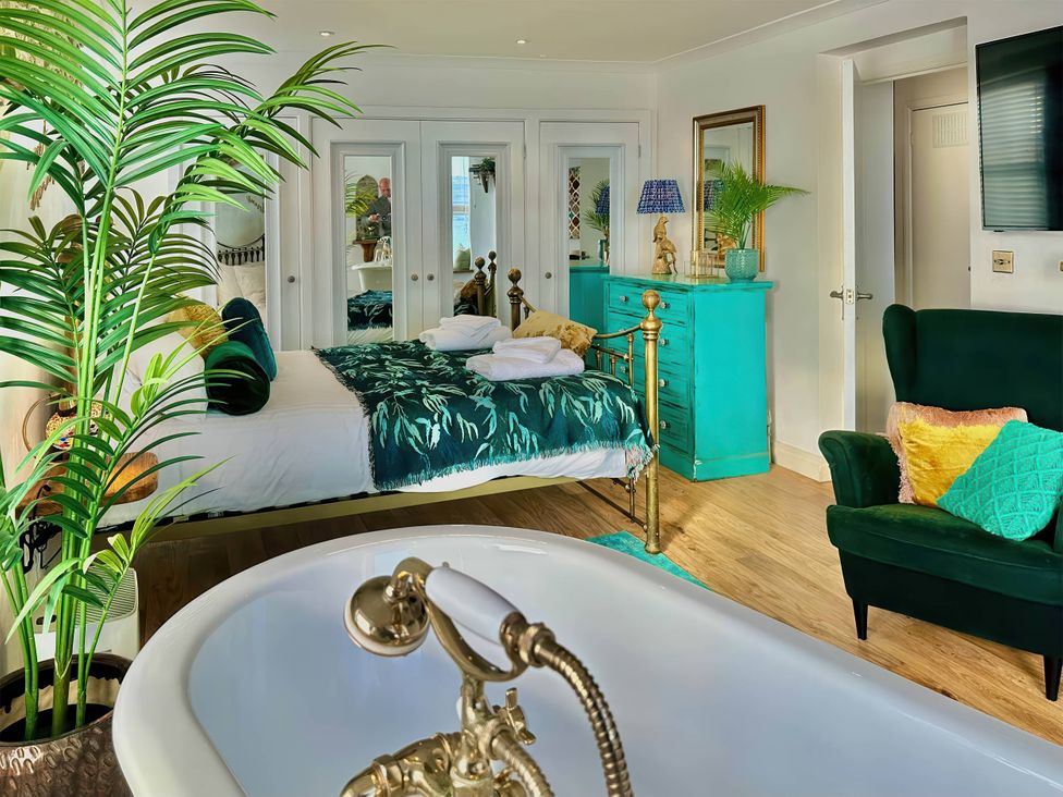 A bedroom with a bathtub and a bed at The Old Barn in Manchester