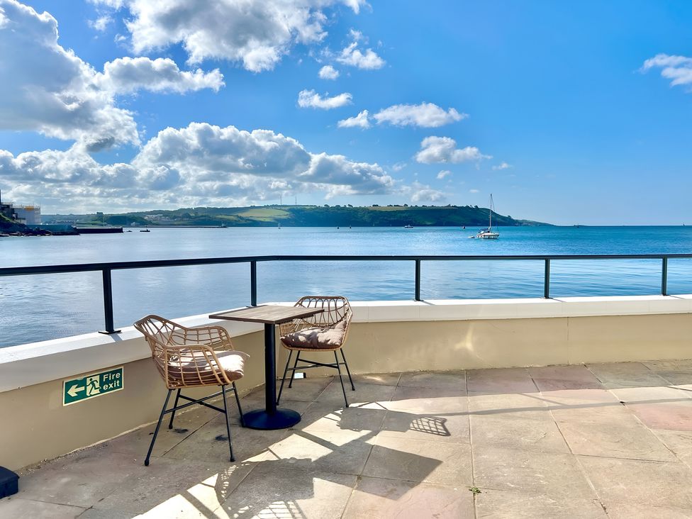An outdoor seating area with two chairs and a table overlooking the water at Seafront Cottage