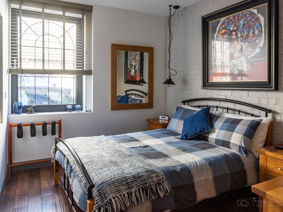 A bedroom with a bed, nightstand, and window at The Old Barn in Manchester