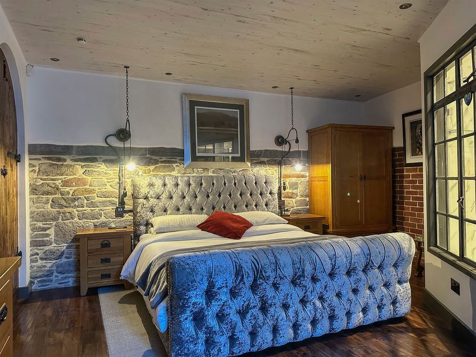A bedroom with a tufted bed and wooden furniture at The Old Barn in Manchester