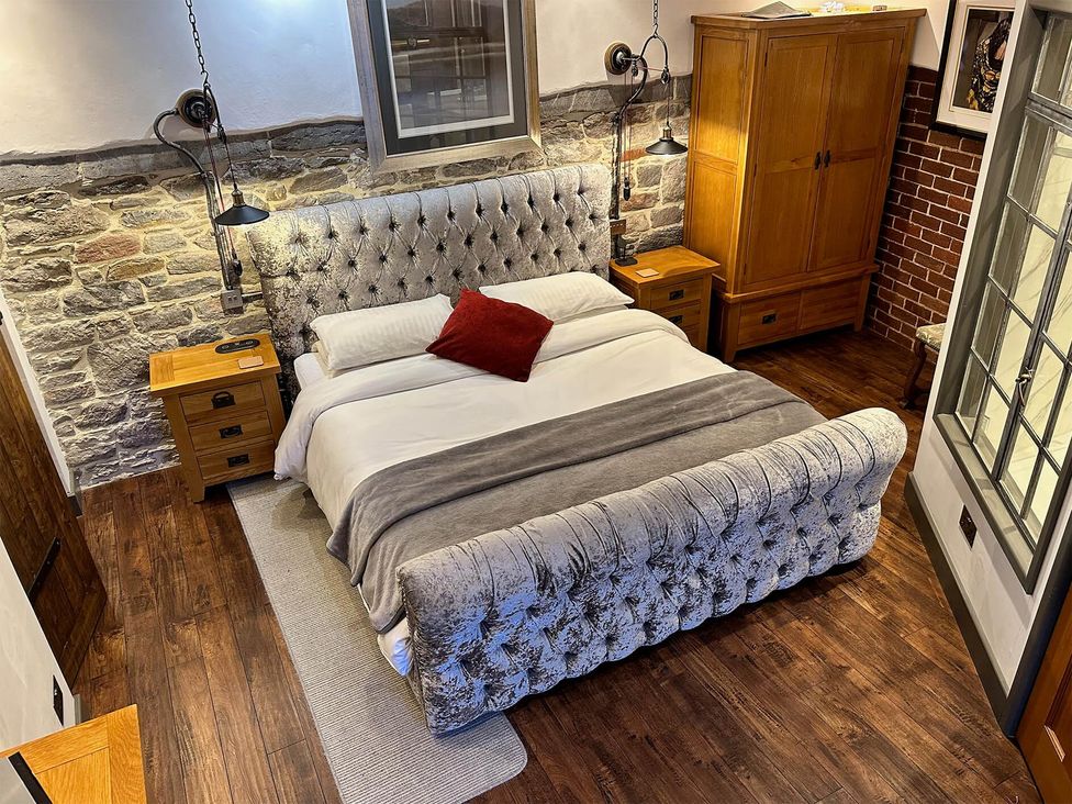A bedroom with a bed and wooden furniture at The Old Barn in Manchester