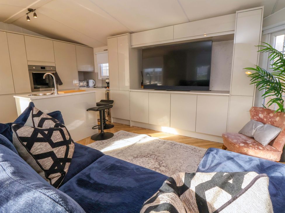A living room with a television and kitchen unit at Lodge in Talacre