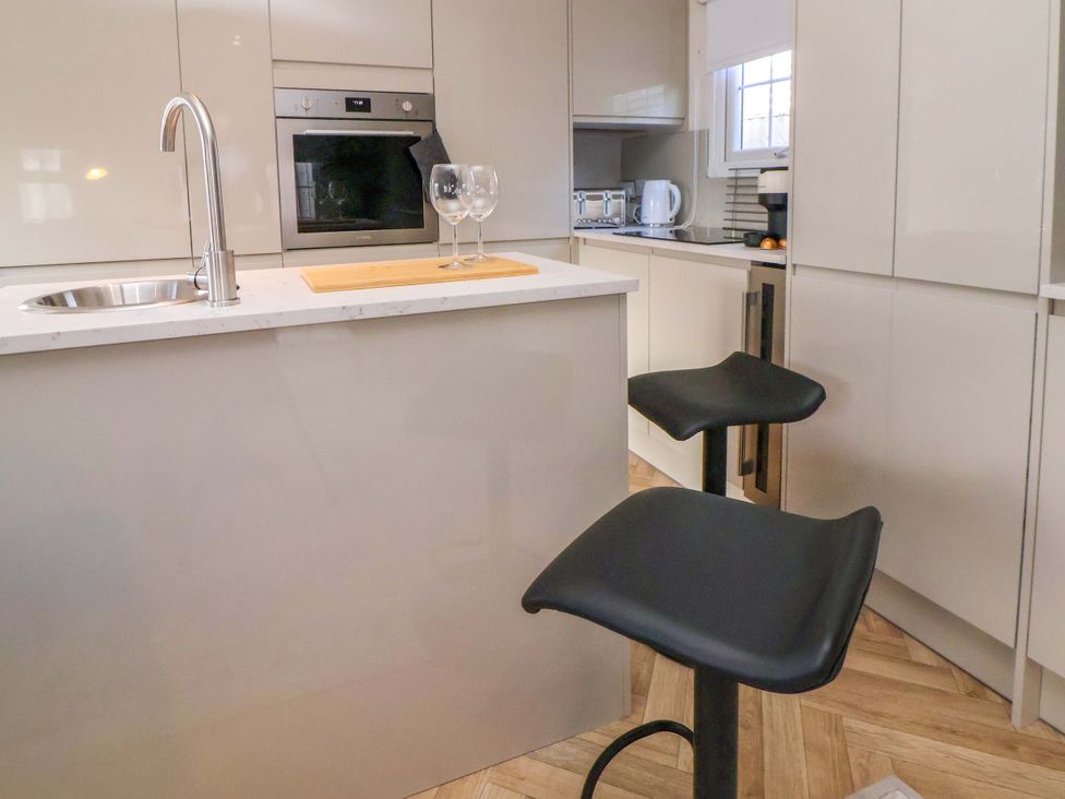 A kitchen with a sink and bar stools at Lodge in Talacre