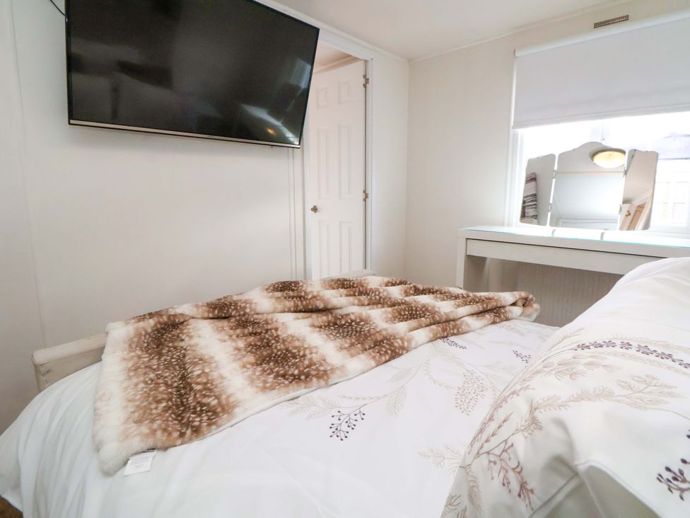 A bedroom with a TV and a bed at Lodge in Talacre