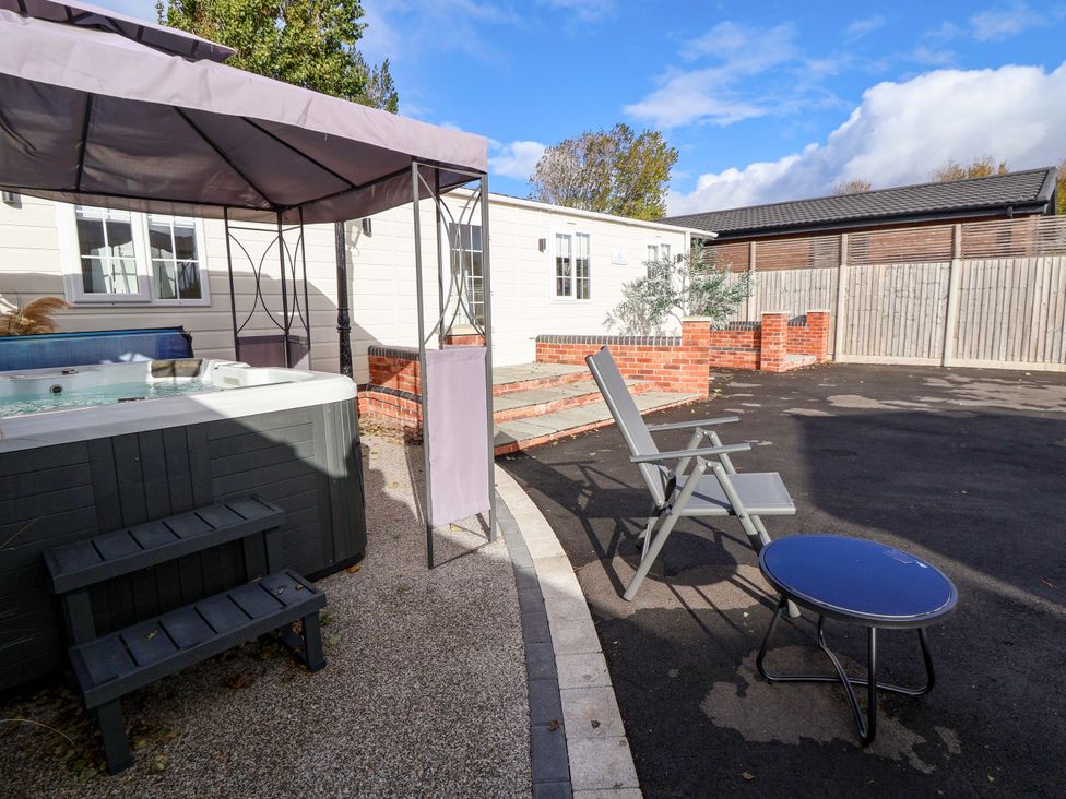 An outdoor area with a hot tub and seating at Lodge Talacre