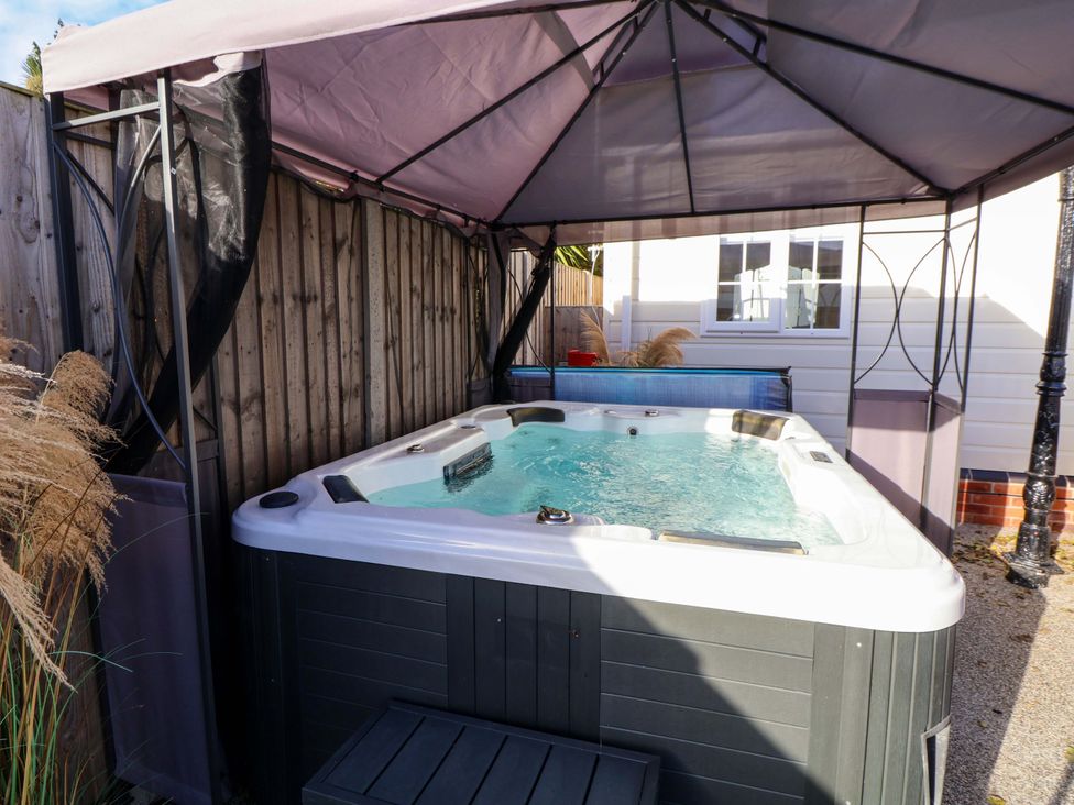 A hot tub under a canopy in an outdoor area at Lodge Talacre