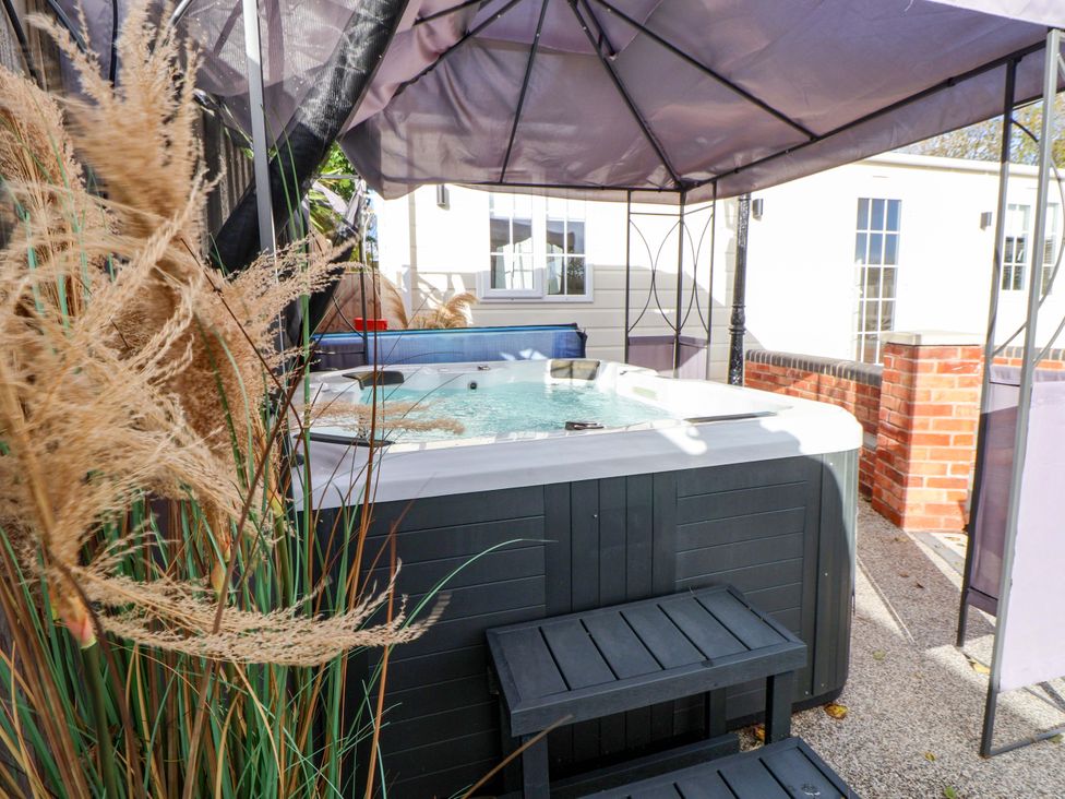 A hot tub under an umbrella at Lodge in Talacre