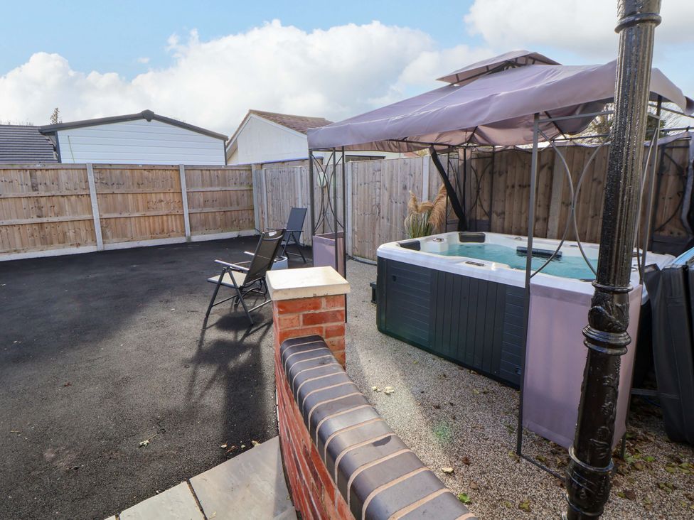 An outdoor area with a hot tub and chairs at Lodge in Talacre