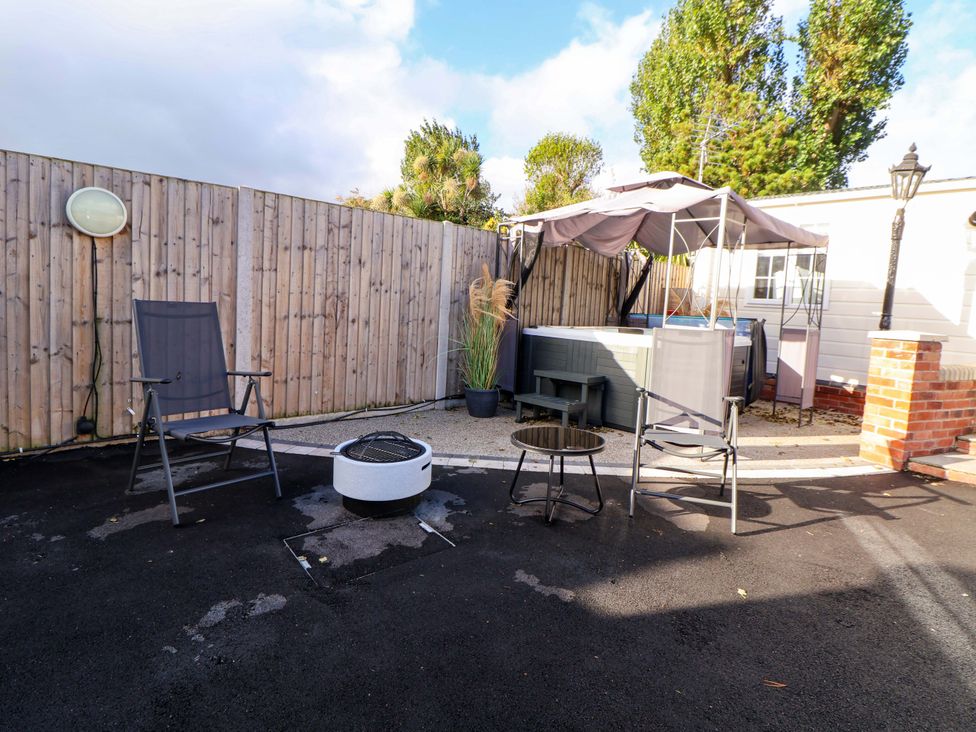 An outdoor seating area with chairs and a hot tub at the Lodge in Talacre