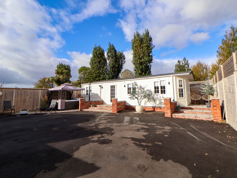 An outdoor area with a cabin, seating, and landscaping at Lodge Talacre