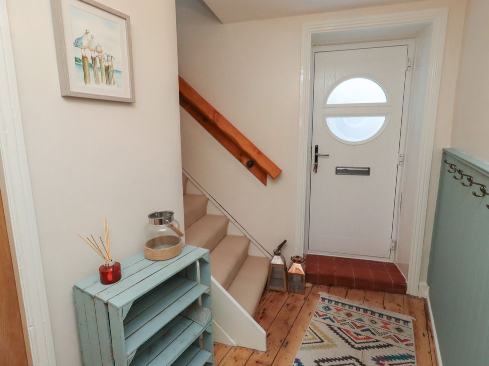 A hallway with a staircase and door at Corner Cottage in Seahouses
