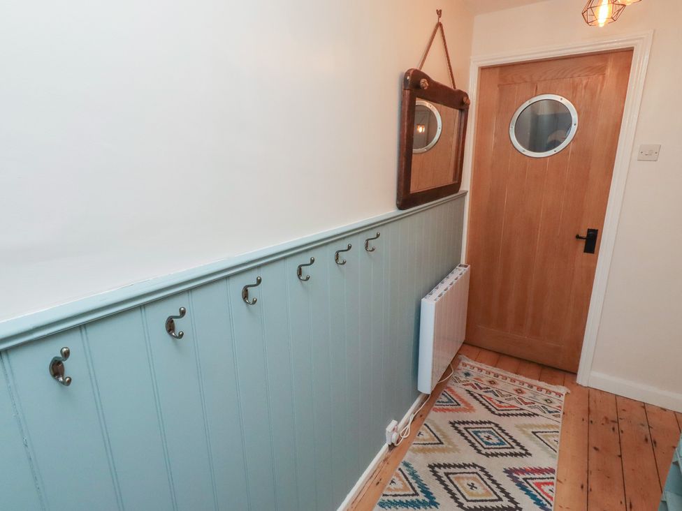 A hallway with hooks and a mirror at Corner Cottage in Seahouses