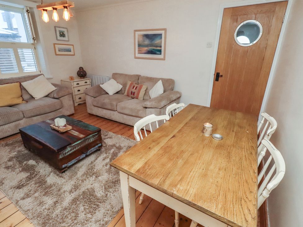 A living room with a dining table and sofas at Corner Cottage in Seahouses