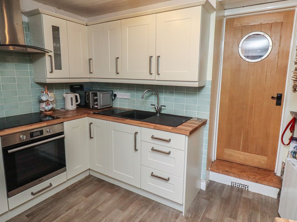 A kitchen with cabinets and appliances at Corner Cottage in Seahouses