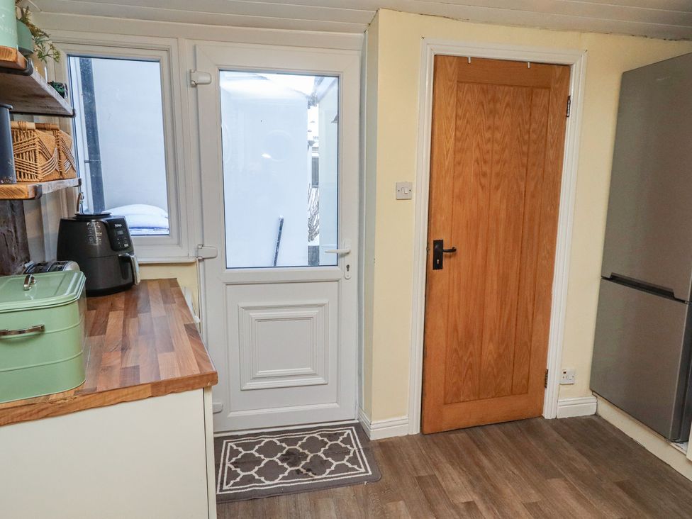 A kitchen with a door and appliances at Corner Cottage in Seahouses