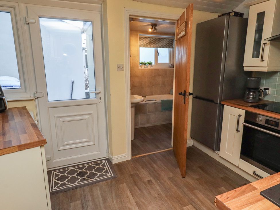 A kitchen with a door and access to bathroom at Corner Cottage in Seahouses