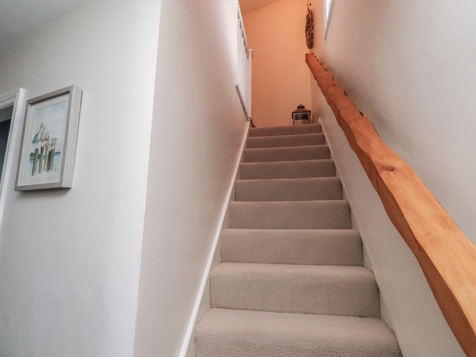 A stairway with a handrail and framed artwork at Corner Cottage in Seahouses