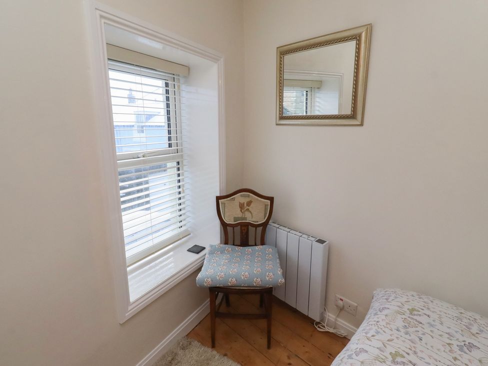 A chair near a window and mirror at Corner Cottage in Seahouses