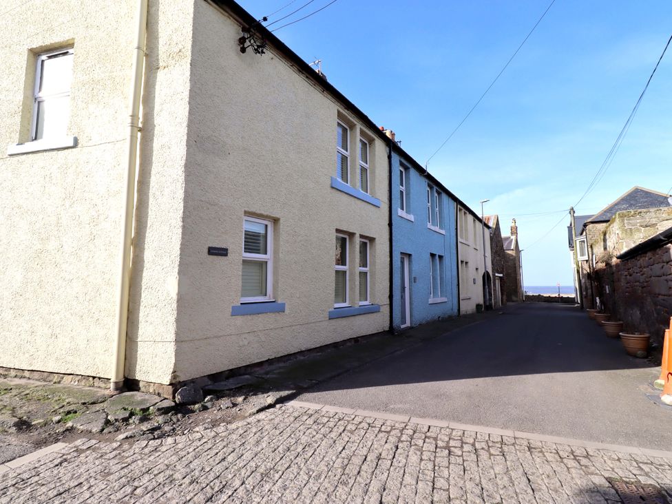 A street view showing buildings and flower pots at Corner Cottage in Seahouses