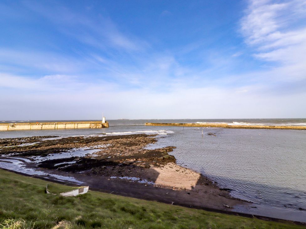 A view of the sea with rocks and a pier at Corner Cottage in Seahouses