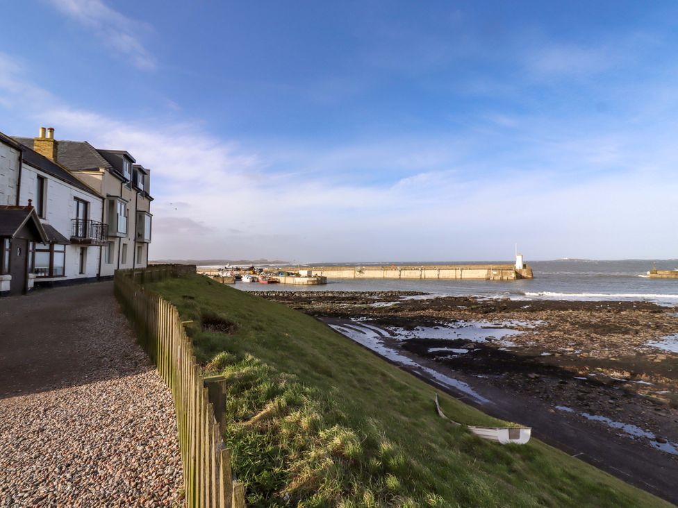 An outdoor area with buildings and a view of the water at Corner Cottage in Seahouses