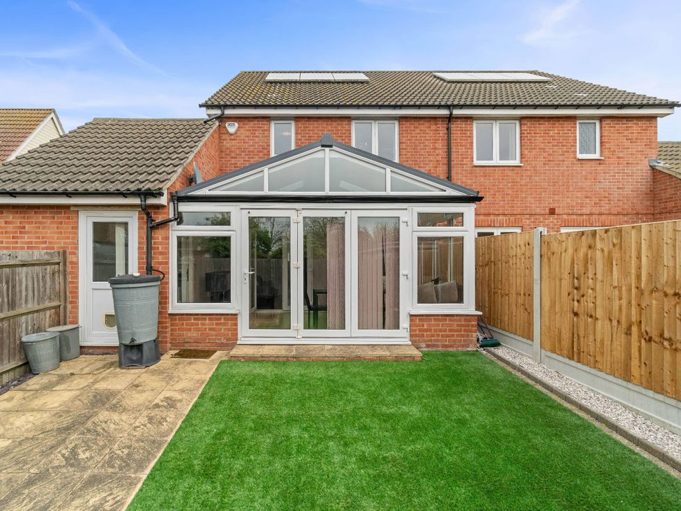 A conservatory with glass doors and a garden at the property