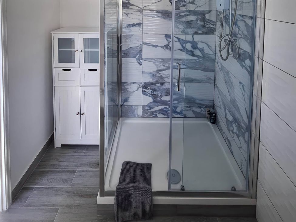 A bathroom with a glass shower and a white cabinet at the property in location