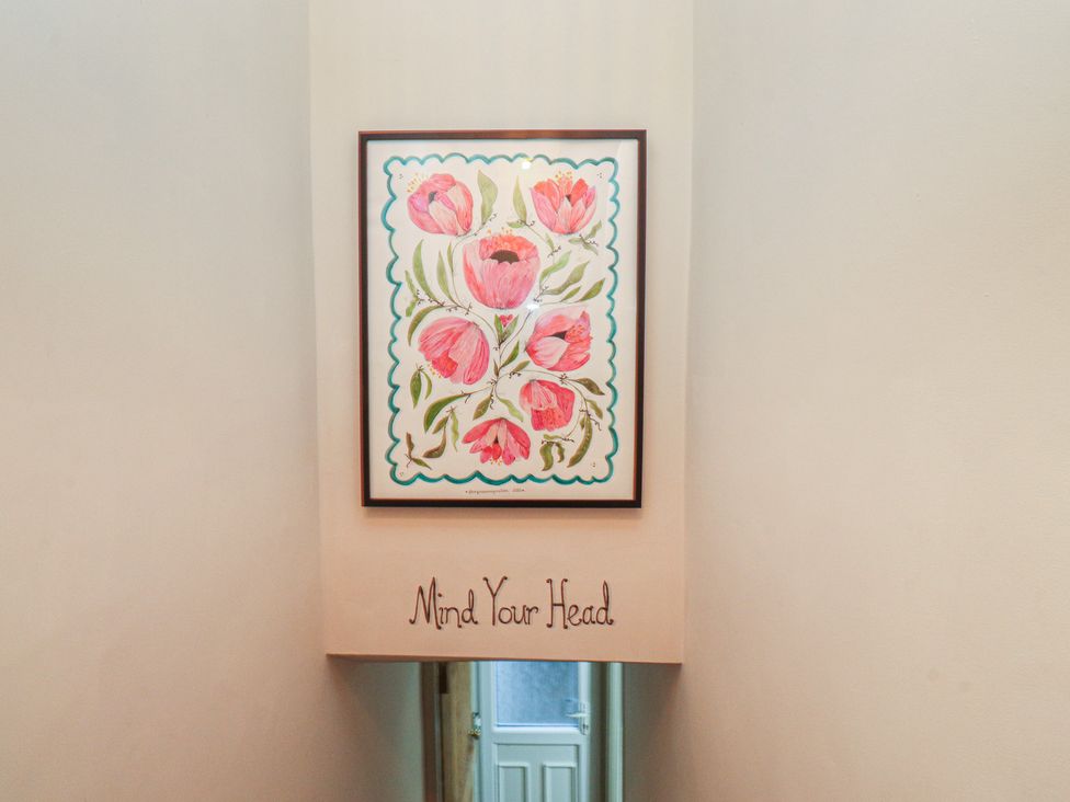 A hallway with a painting and text 'Mind Your Head' at Levenside in Preston