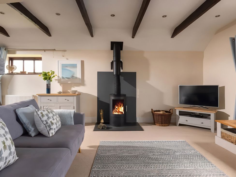 A living room with a fireplace and a television at The Granary near St Merryn