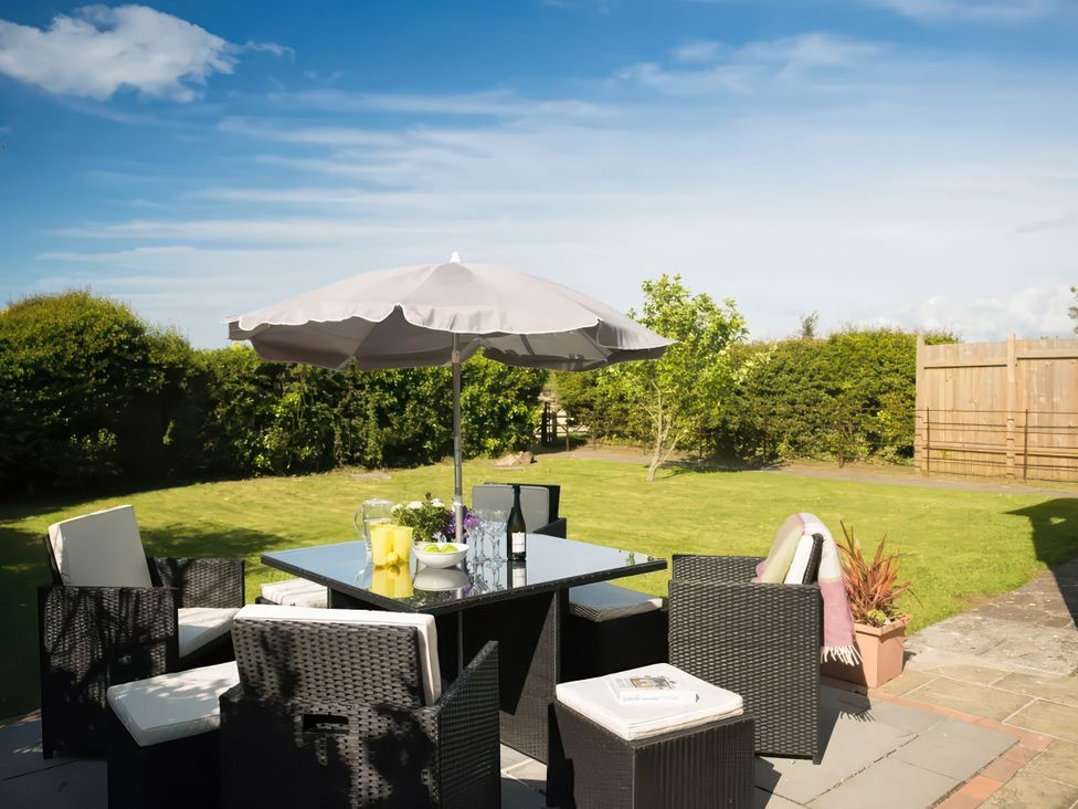 A garden with a table and chairs under an umbrella at The Granary near St Merryn