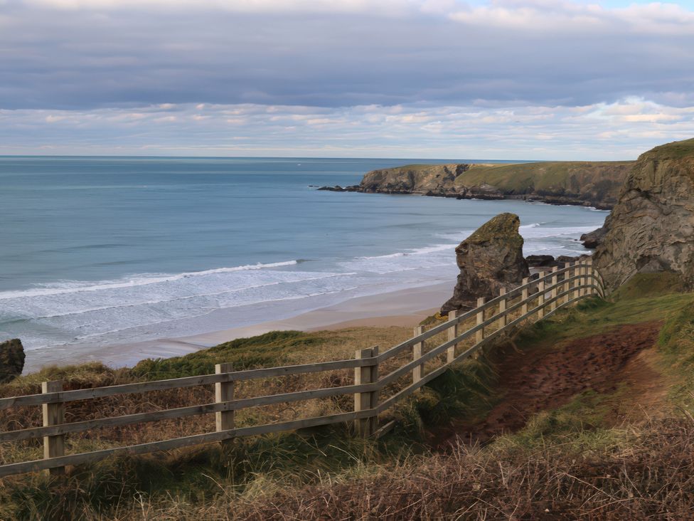 A view of a beach and ocean with a fence at The Granary, Engollan near St Merryn