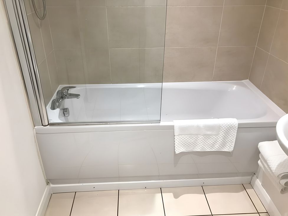 A bathtub with a shower and towels in a bathroom