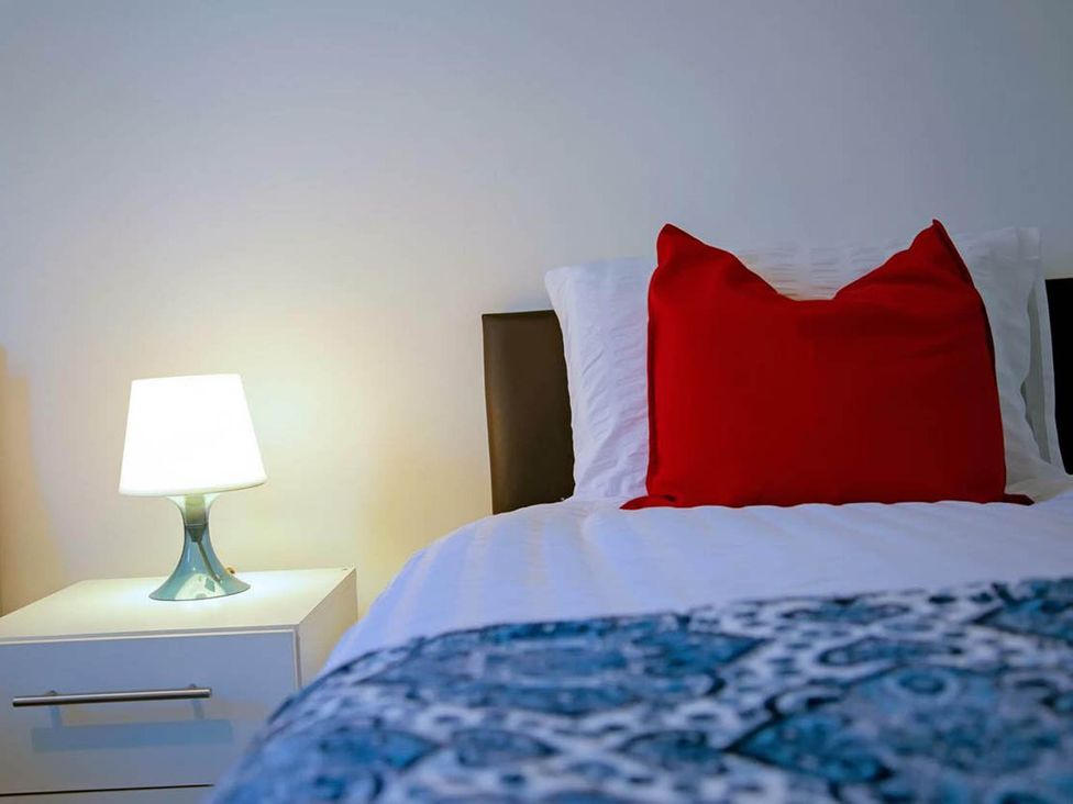 A bedroom with a bed and a lamp on a nightstand at 