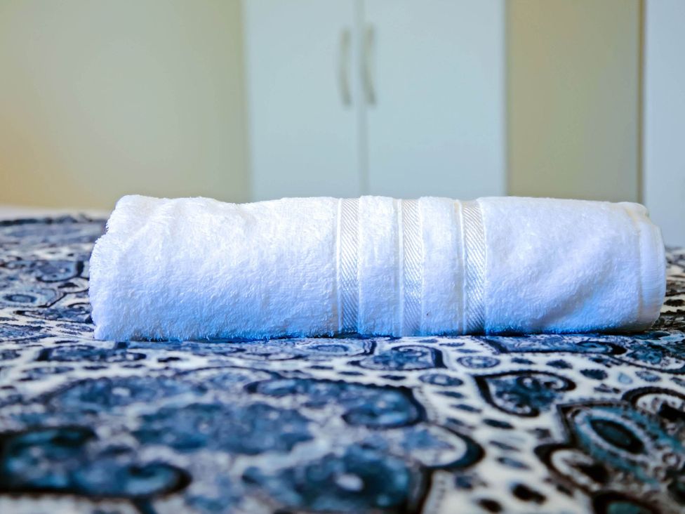 A rolled towel on a bedspread at an unspecified location