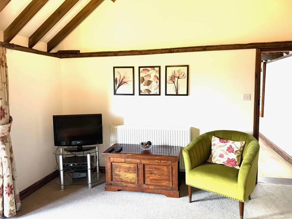A living room with a tv and armchair at The Old Barn in Manchester