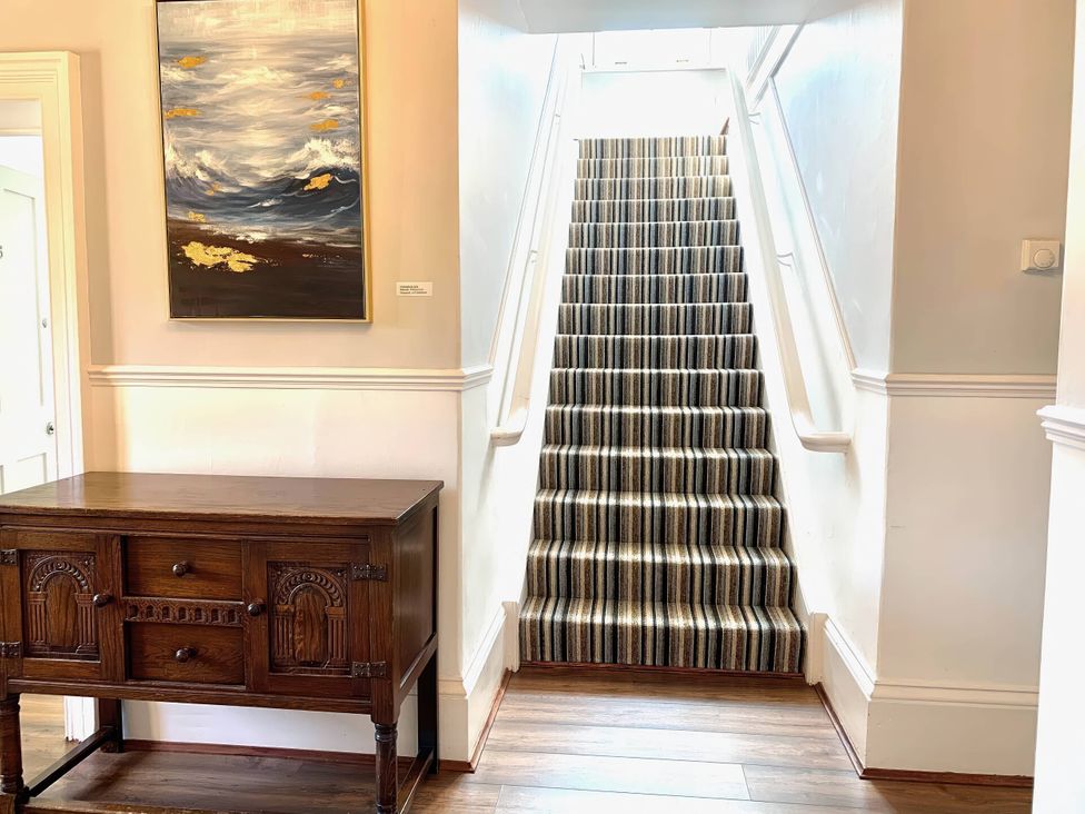 A hallway with a staircase and a chest of drawers at The Old Barn in Manchester