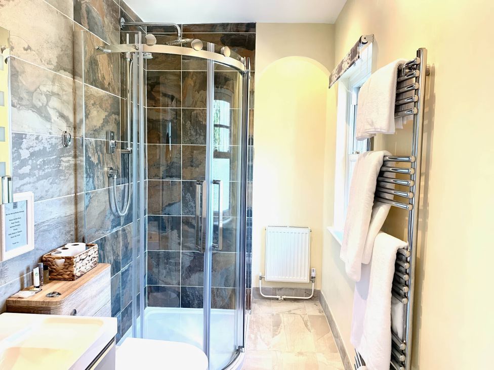 A bathroom with a shower, sink, towels, and radiator at 